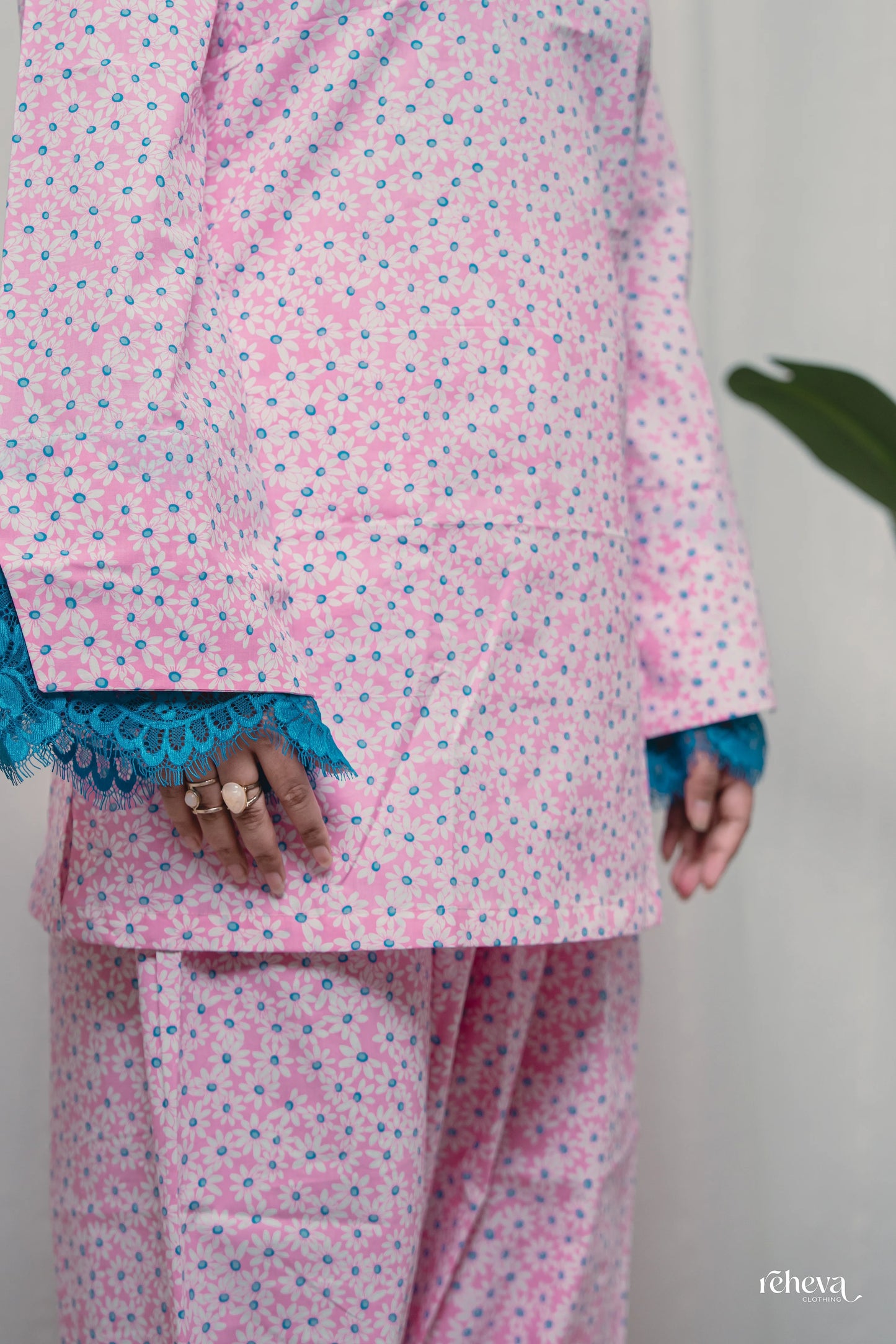 A person wearing a pink and blue floral print pajama set with blue lace trim on the cuffs, shown from the chest down against a light background.